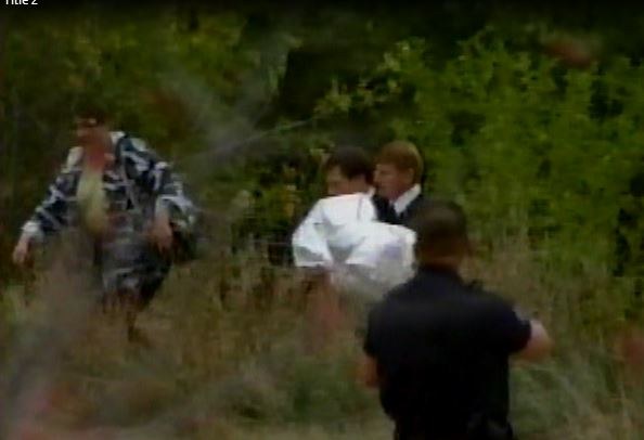 Mark Crider carrying a child wrapped in white cloth up an embankment during a scene response