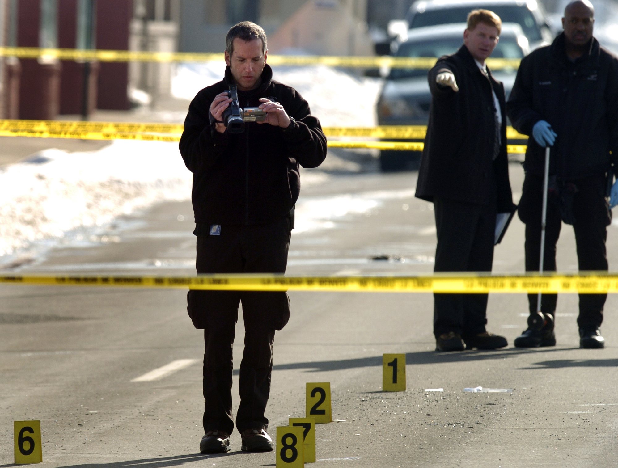 Investigators documenting a taped-off roadway crime scene