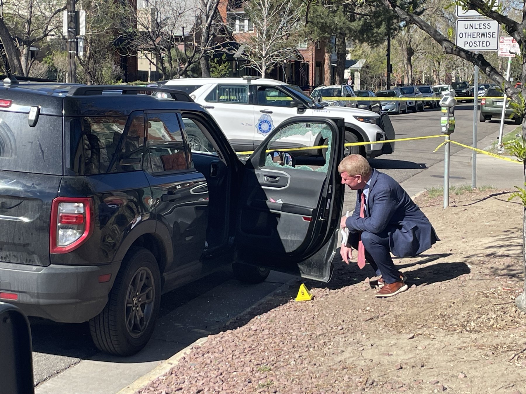 Mark Crider squatting beside a vehicle during scene documentation